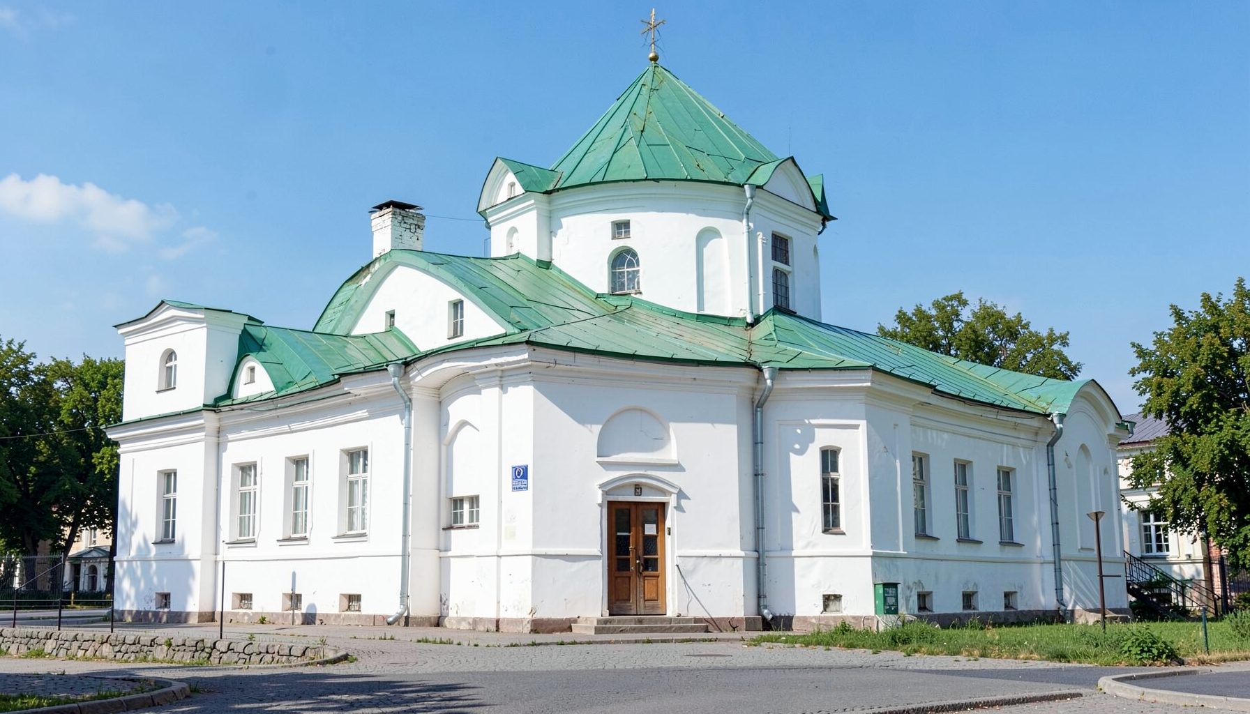 Фасад Ковнировского корпуса Киево-Печерской лавры, белые стены с зелёной крышей, солнечный день